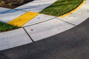 curb with a shallow slope and bright yellow pad with raised dots, two of the safety features we can install