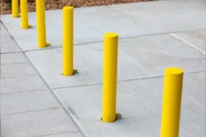 yellow painted parking lot bollards installed on concrete on commercial property