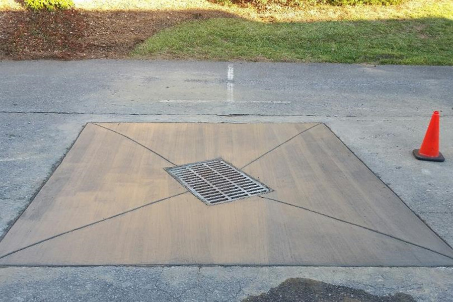 Utility drain with fresh concrete pavement surrounding it.