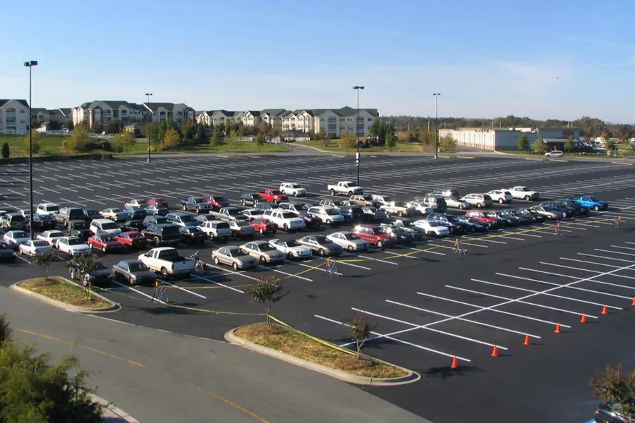 Aerial view of a large parking lot with cars parked. The asphalt pavement and line striping has been recently redone.