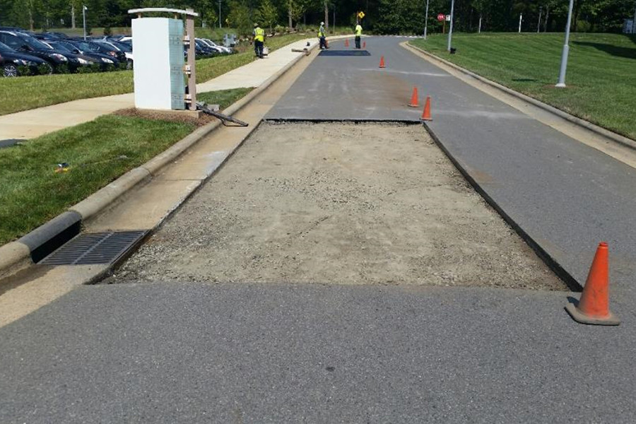 Large patch of asphalt has been removed and Carolina Asphalt workers can be seen in the background working on another asphalt pavement repair.