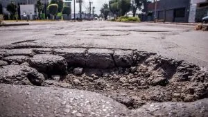 Pothole that needs pothole repair in the middle of a empty road