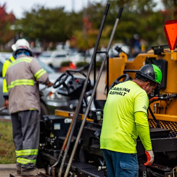 two carolina asphalt workers with safety gear working on a paving machine