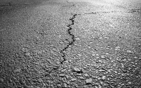 Linear crack in asphalt pavement showing damage that may allow water intrusion