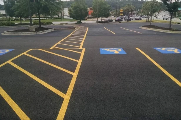Commercial asphalt parking lot with fresh yellow striping and ADA accessible parking spaces.
