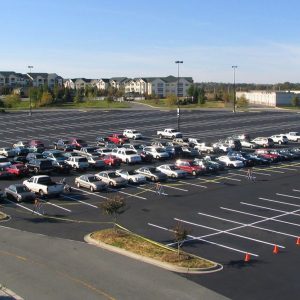 Aerial view of a large parking lot with cars parked. The asphalt pavement and line striping has been recently redone.
