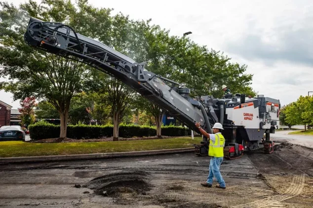asphalt milling machine on a patch of dirt overlay with a paving contractor directing the machine