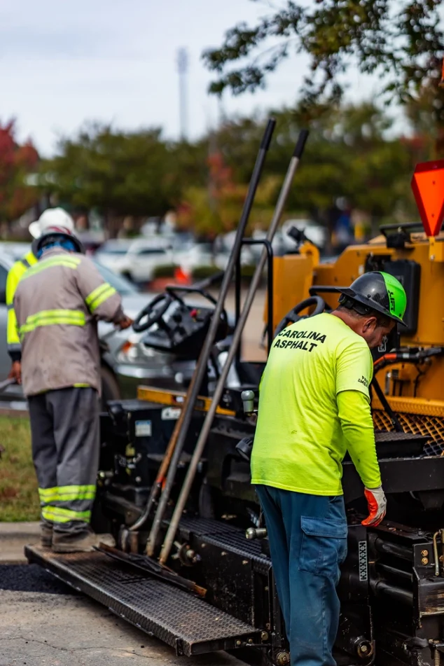 two carolina asphalt workers with safety gear working on a paving machine