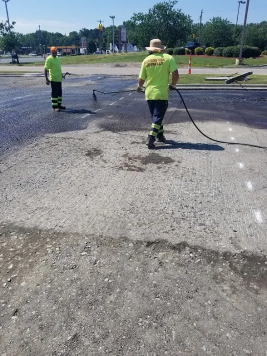 Carolina Asphalt crew applying sealcoating to a commercial parking lot