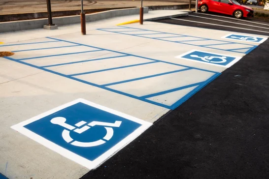 Freshly painted ADA parking lot markings with accessible parking spaces and blue wheelchair symbols.